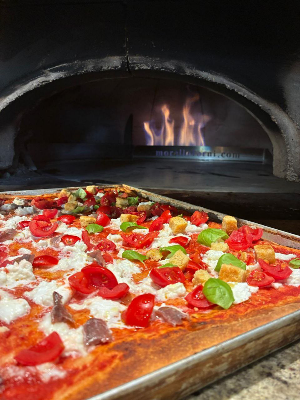 Pizza nel forno con la fiamma viva